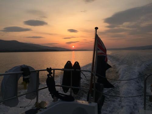 two people sitting on the back of a boat at sunset at Argyll Mansions in Oban