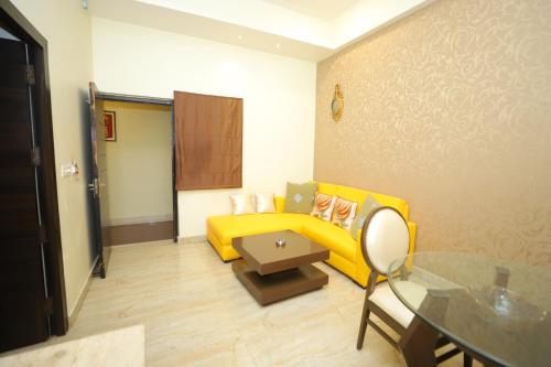 a living room with a yellow couch and a table at JM Vistaraa in Bareilly