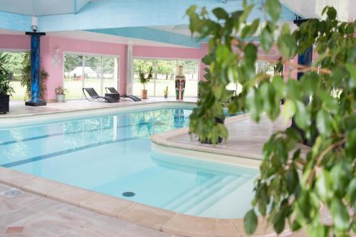 una piscina con acqua blu in un edificio rosa di Domaine de Bertheauville a Paluel