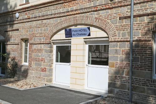 a brick building with two white doors and a sign on it at Domaine de Bertheauville in Paluel