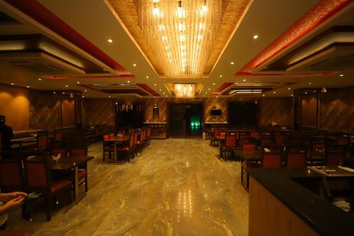 a dining room with tables and chairs and a chandelier at JM Vistaraa in Bareilly