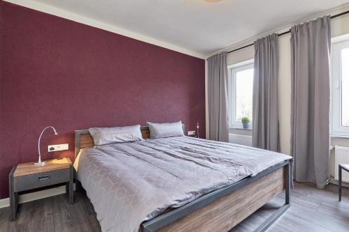 1 dormitorio con 1 cama grande y pared morada en Haus Blanka, en Brauneberg
