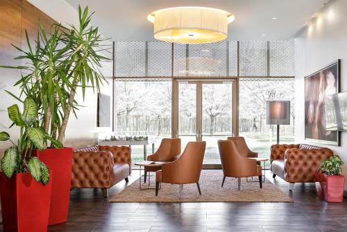 eine Lobby mit Stühlen, einem Tisch und großen Fenstern in der Unterkunft Asia Hotel & Spa Leoben in Leoben