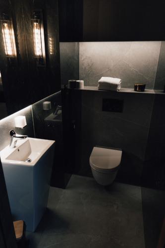a bathroom with a white toilet and a sink at Hotel Loft 1898 in Suwałki