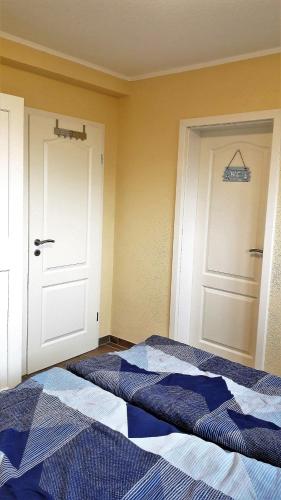 a bedroom with a blue and white bed and a door at Küstenhuus-Katy in Glowe