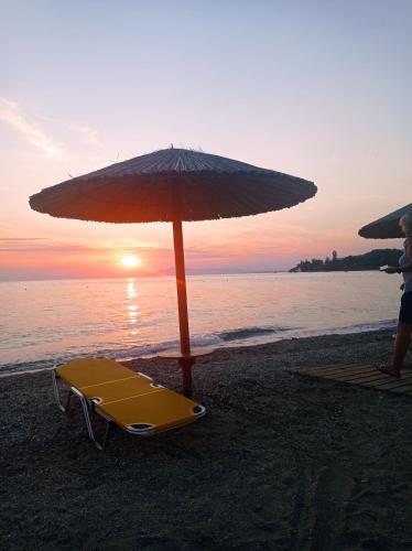a beach with an umbrella and a chaise lounge at Poly's Sea Side House in Koropi