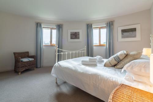 um quarto com uma cama, uma cadeira e janelas em The Roundhouse em Wadebridge