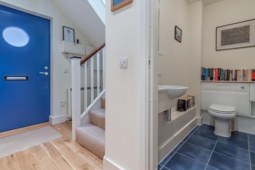 a bathroom with a toilet and a staircase with a blue door at 4 Pentire Rocks in Polzeath