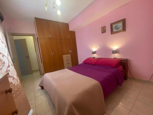 - une chambre avec des murs roses et un lit avec des draps violets dans l'établissement Galini Apartment, à Karpathos