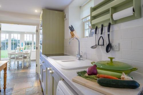 a kitchen with a sink and vegetables on a counter at Balwest Cottage in Helston