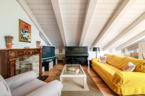 a living room with a yellow couch and a piano at Castello di Brusata by Quokka 360 - romantic flat with pool in Mendrisio