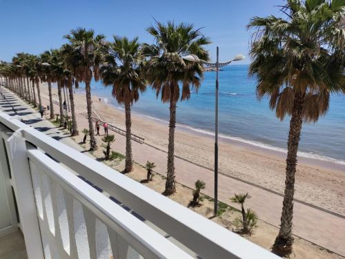 a balcony with a view of the beach and palm trees at Beach front Esther 5 villajoyosa in Villajoyosa