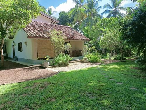 een huis met een grasveld ervoor bij John's Homestay in Talpe