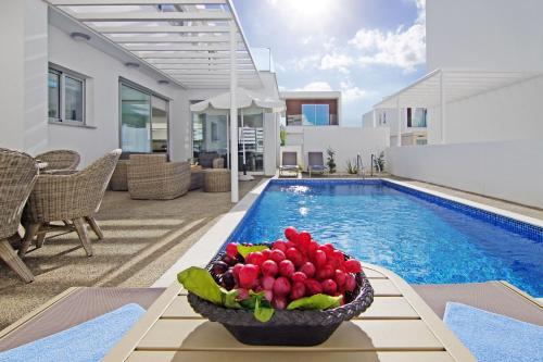 - un bol de fruits sur une table à côté de la piscine dans l'établissement Villa Violanta, à Ayia Napa