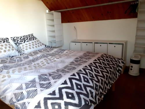 a bedroom with a bed with a black and white comforter at Studio privé aux portes des Fagnes in Polleur