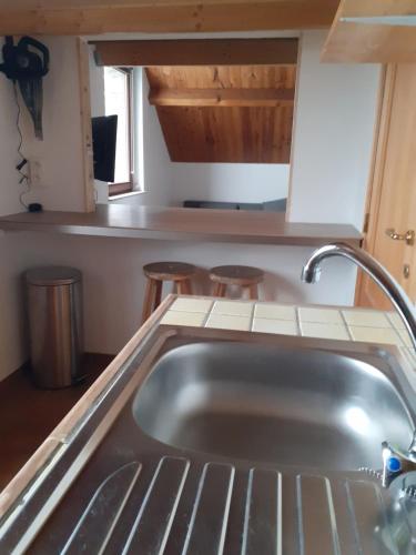 cocina con fregadero y 2 taburetes en Studio privé aux portes des Fagnes en Polleur