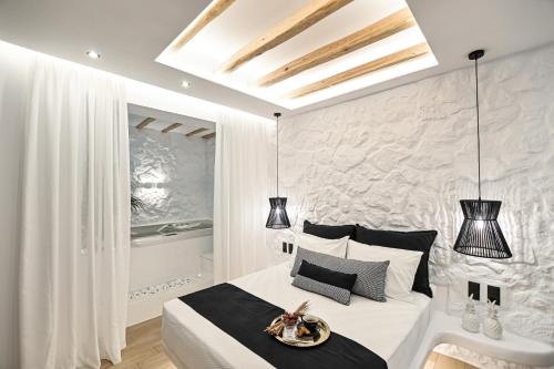 a bedroom with a white bed and a stone wall at Mythos Luxury Suite in Naxos Chora