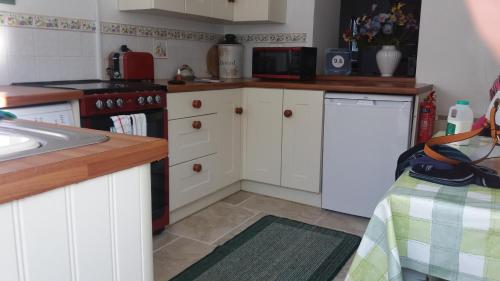 a kitchen with white cabinets and a stove and a sink at Pen Llyn Quarryman's Cottage in Trevor