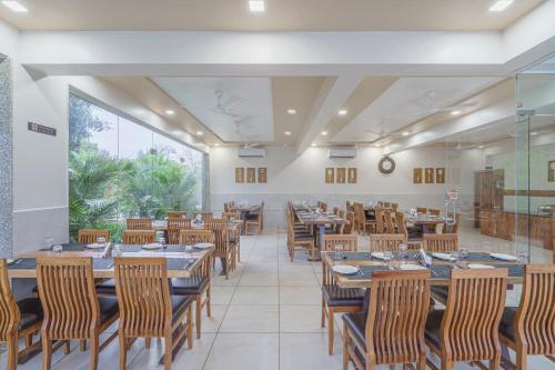 a restaurant with wooden tables and chairs and a large window at Sterling Gir in Sasan Gir