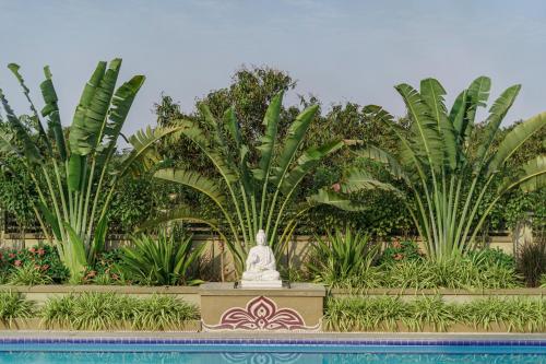 a statue in a garden with palm trees at Sterling Gir in Sasan Gir