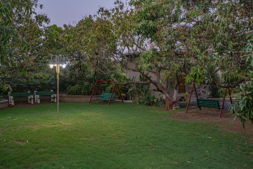 a park with two green benches and a playground at Sterling Gir in Sasan Gir
