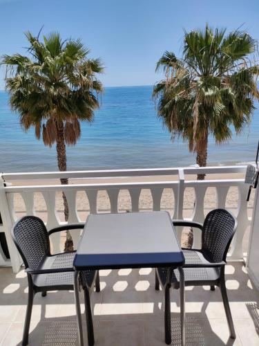 einen Tisch und Stühle auf einem Balkon mit Strandblick in der Unterkunft Beach front Esther 6 villajoyosa in Villajoyosa