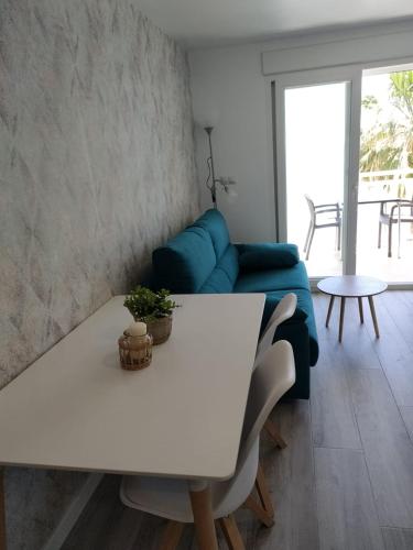 ein Wohnzimmer mit einem weißen Tisch und einem blauen Sofa in der Unterkunft Beach front Esther 6 villajoyosa in Villajoyosa