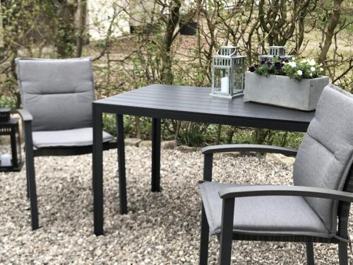 ein schwarzer Tisch, 2 Stühle und ein Tisch mit Blumen in der Unterkunft Ferienwohnung Landhaus in Maasbüll