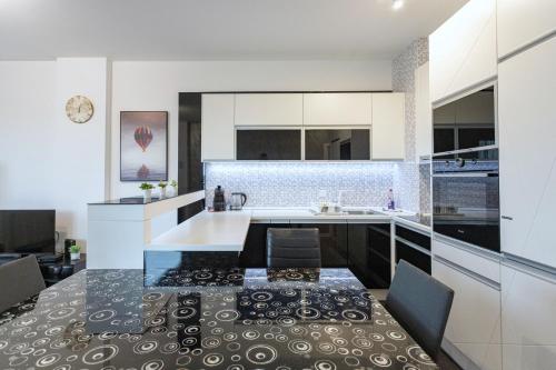a kitchen with white cabinets and a black and white counter top at Pleasure Lux1 Apartment in Belgrade