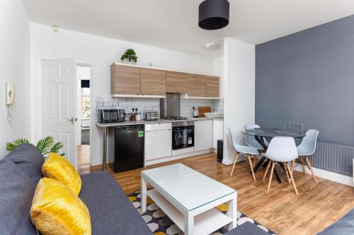 a kitchen and a living room with a couch and a table at FLATZY - Stylish Abode on Doorstep of Sefton Park *10 minutes to Centre* in Liverpool