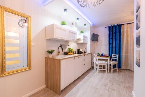 a kitchen with white cabinets and a table and a mirror at Apartament Kasztelan in Ustrzyki Dolne
