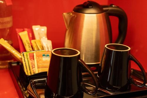 two black mugs on a stove with a tea kettle at IntercityHotel Dubai Jaddaf Waterfront in Dubai