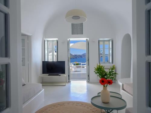 a white living room with a vase of flowers on a table at Lathouri Cave Villa in Oia