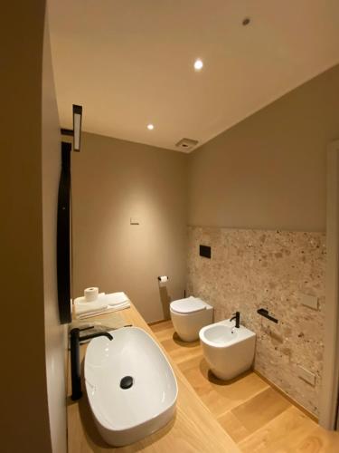 a bathroom with two toilets and a sink and a tub at Tenuta Pizzone Wine Resort in Rivanazzano
