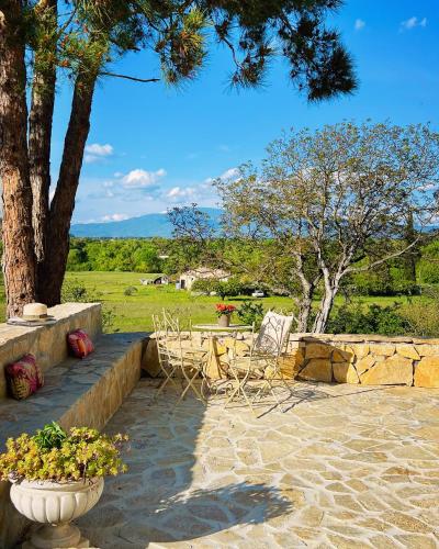 a stone patio with two chairs and a tree at Domaine de La Brave in Pernes-les-Fontaines