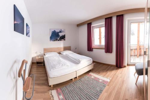 een slaapkamer met een bed, een stoel en ramen bij Appartment Waldheim in Sesto