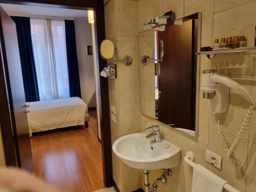 a bathroom with a sink and a mirror and a bed at Phi Hotel Bologna in Bologna