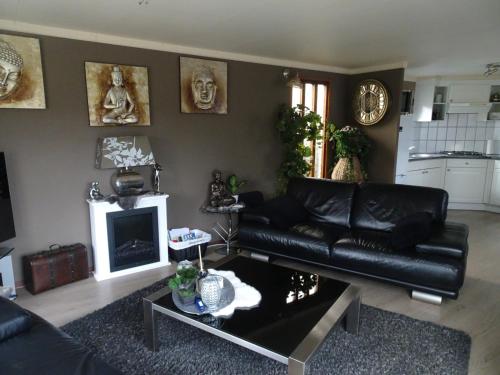 a living room with a black leather couch and a fireplace at Veluwe Park Reewold Chalet Talisman in Putten
