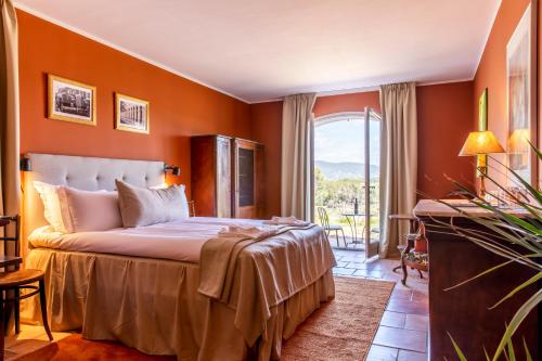 a bedroom with a bed with orange walls and a window at Domaine Rabiega - Vineyard and Boutique hotel in Draguignan