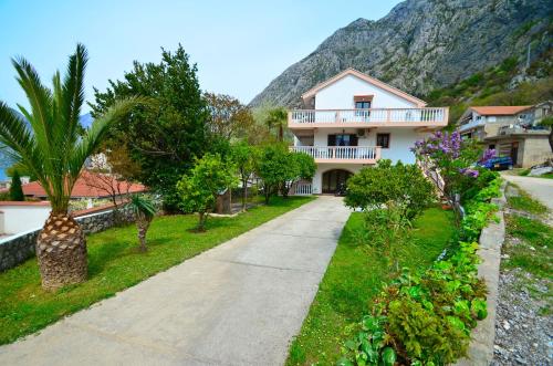 a house on a road with a mountain in the background at Apartments Blue Lagoon in Kotor