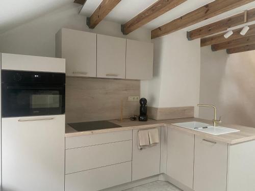 a white kitchen with white cabinets and a sink at Au temps suspendu in Marche-en-Famenne