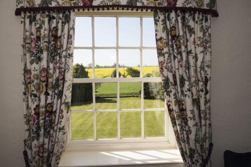 a window with curtains with a view of a field at Mallard Grange B&B in Ripon