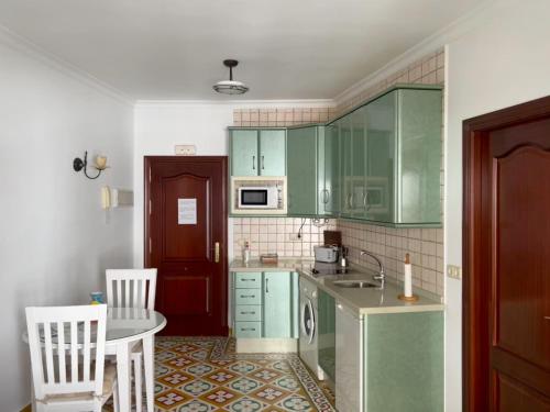 a kitchen with green cabinets and a table and chairs at Apartamentos Trujillo in Tarifa