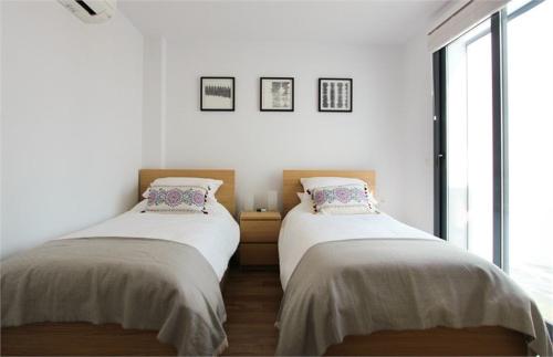 2 łóżka w pokoju z białymi ścianami i oknami w obiekcie Villa Jaz w mieście Torrox