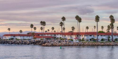 a resort on the shore of the water with palm trees at Oceanside Marina Suites - A Waterfront Hotel in Oceanside