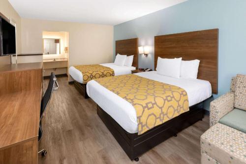 a hotel room with two beds and a chair at Baymont by Wyndham Biloxi - Ocean Springs in Biloxi