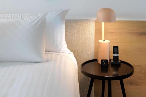 a bed with a phone and a lamp on a table at QT Bondi in Sydney