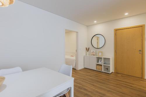 a white bedroom with a door and a wooden floor at Paim XXI Azores Apartment in Ponta Delgada