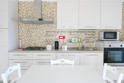 a kitchen with white cabinets and a stove top oven at Casa SavAnna in Torre Lapillo