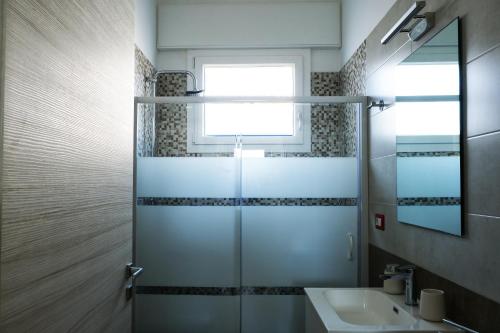 a bathroom with a shower with a sink and a window at Casa SavAnna in Torre Lapillo